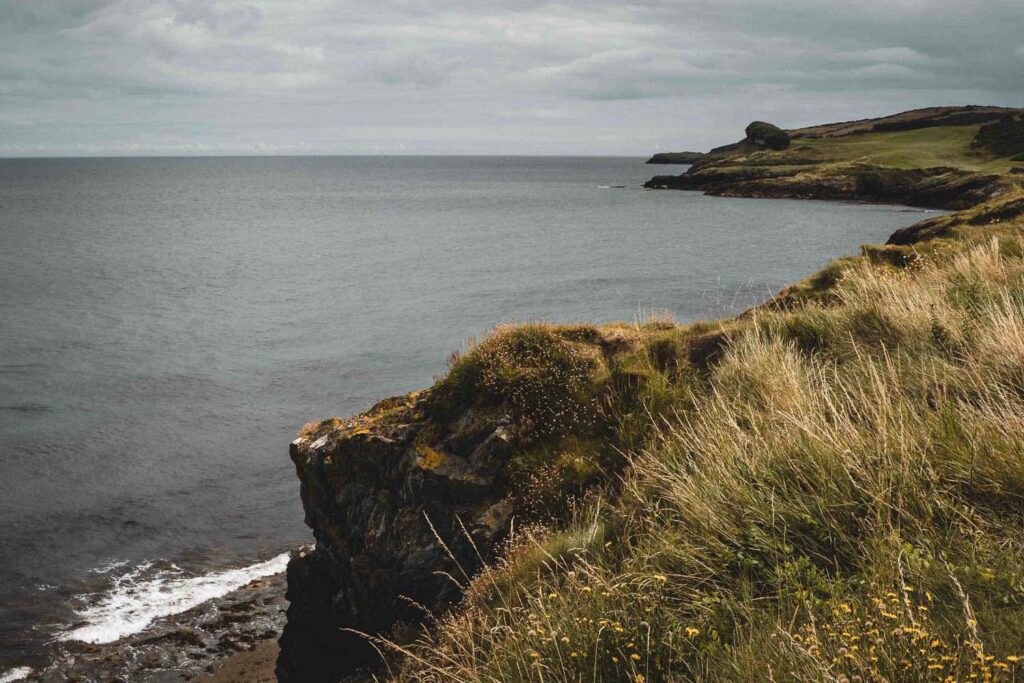 Küstenabschnitt mit grünen Hügeln und grauer See